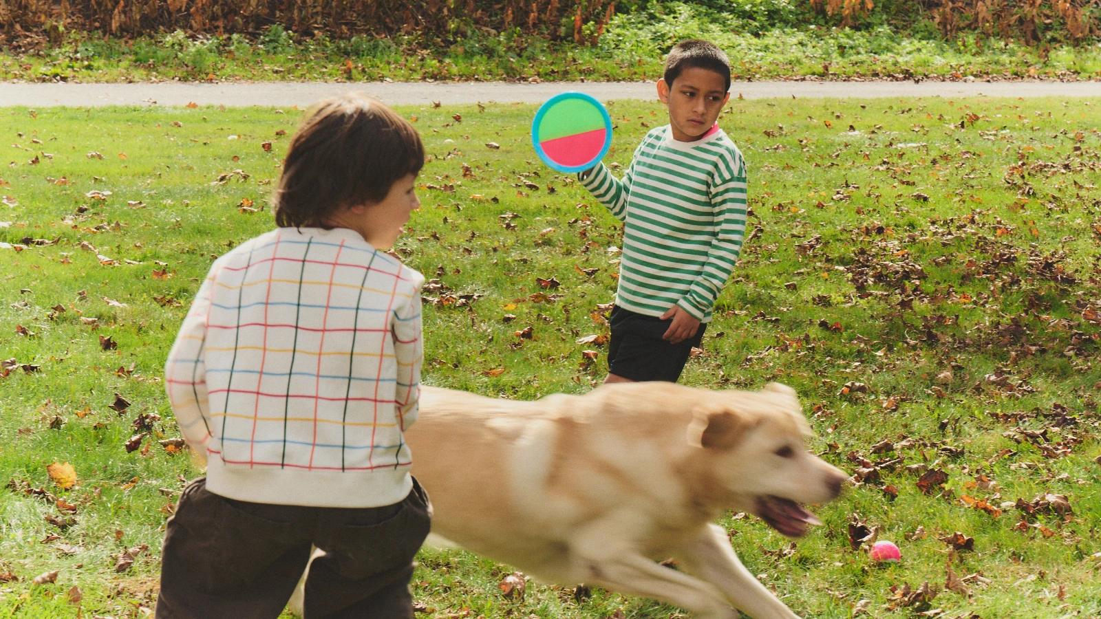 Two children and a dog playing together on a lawn.